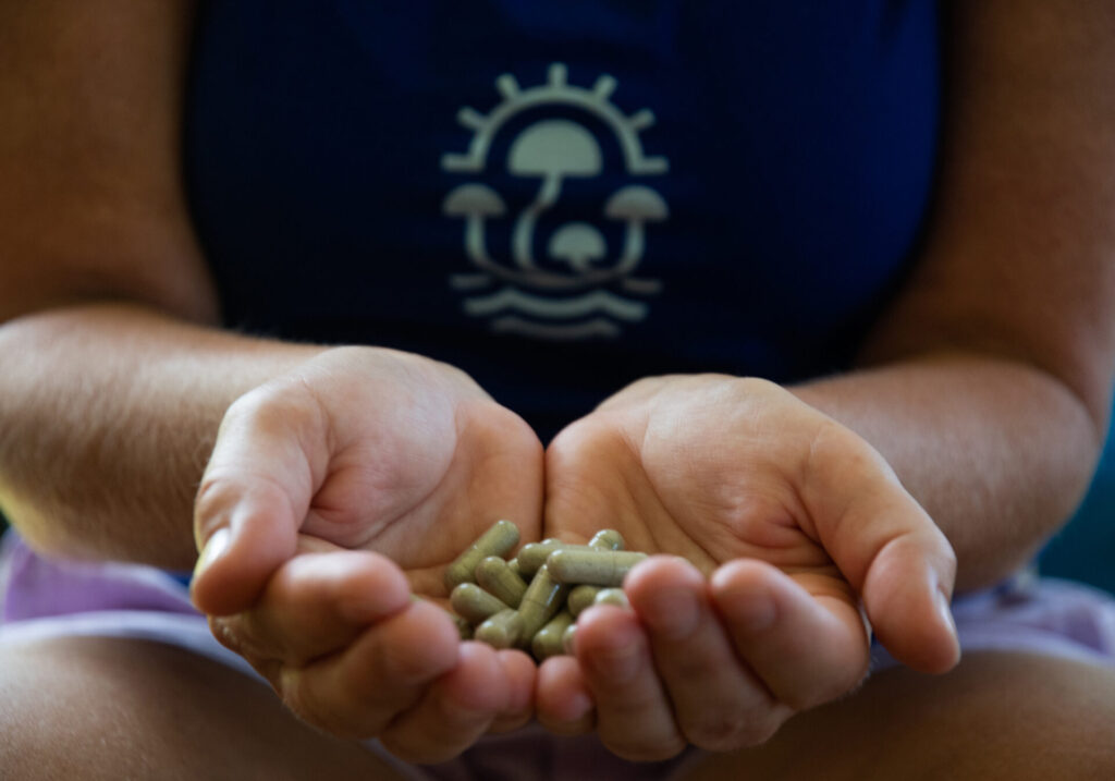 hands holding encapsulated powder of psilocybin mushrooms