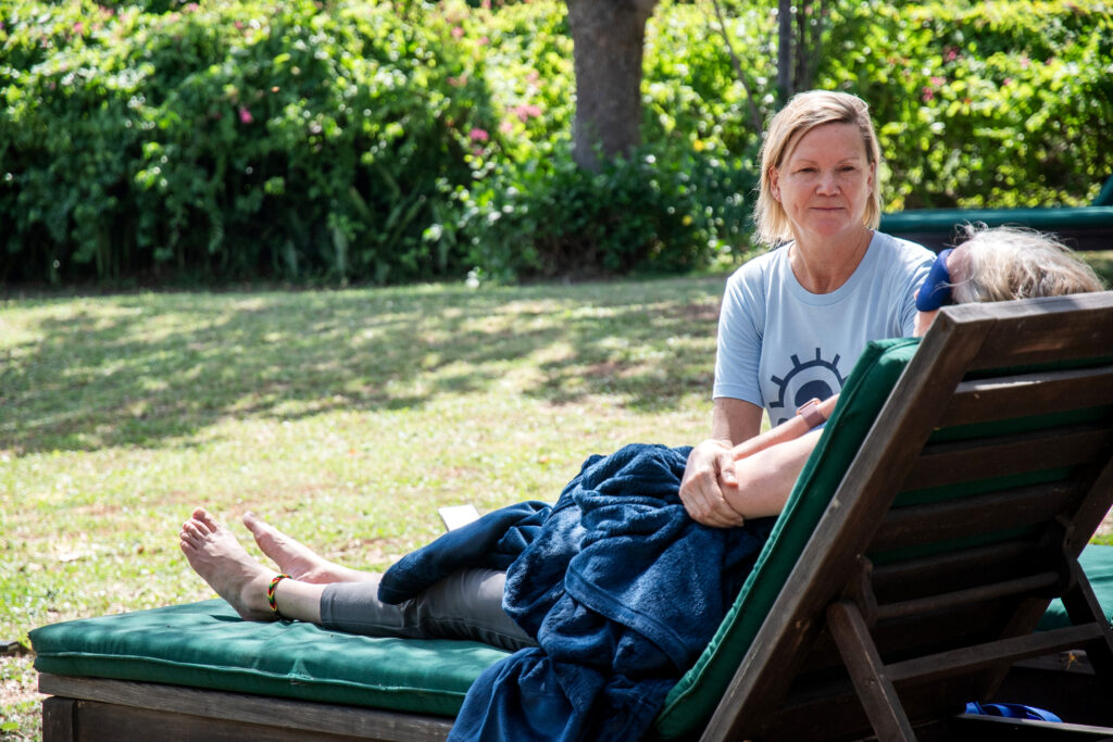psychedelic therapist guiding a client who's laying on a reclined chair through a psilocybin therapy session in a peaceful, green garden.