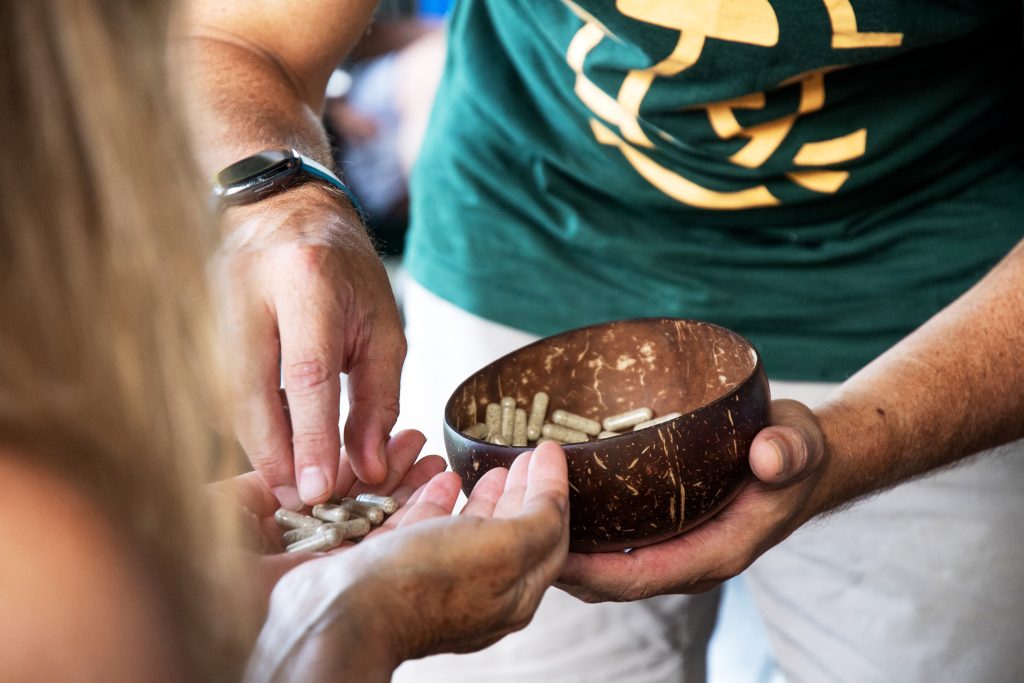 man giving psilocybin mushroom capsulte to woman holding her hands out at mycomeditations