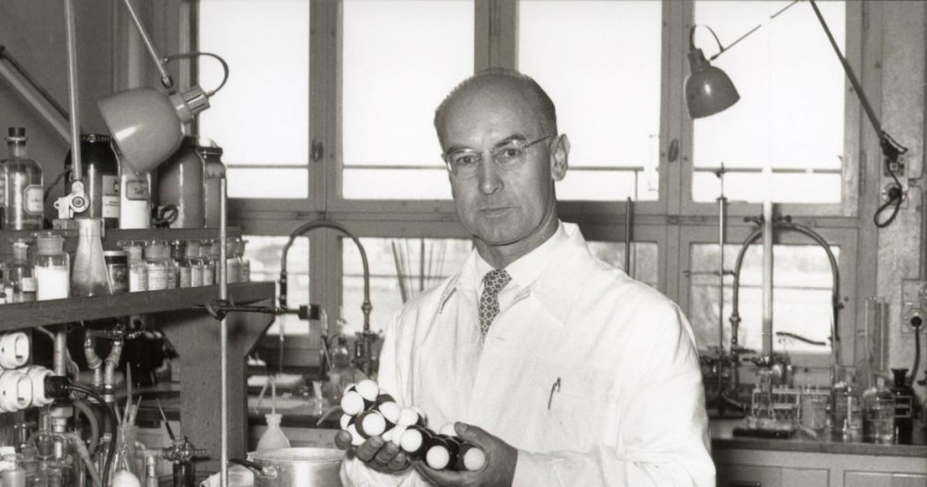 albert hoffman in a lab holding plastic model of the LSD chemical structure