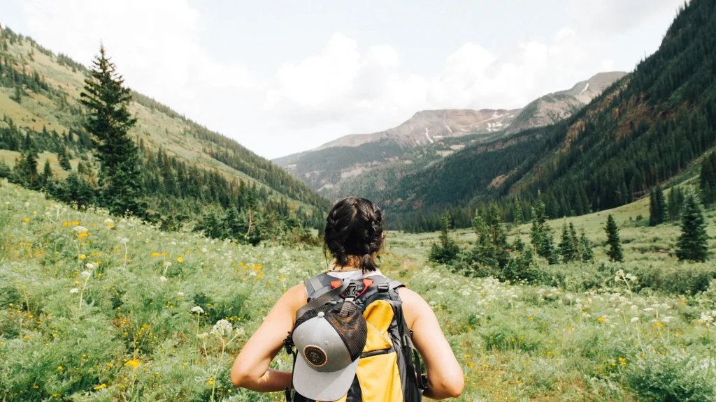 woman hiking through a green mountain valley