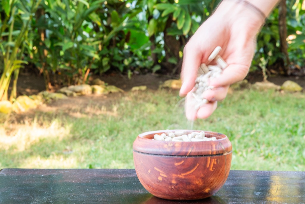 Facilitator puts psilocybin mushroom capsules into a wooden bowl.